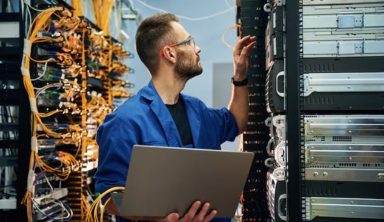 Data engineer in a high-tech server room with server racks and network cables, performing maintenance and monitoring to support cloud computing and enterprise data infrastructure.